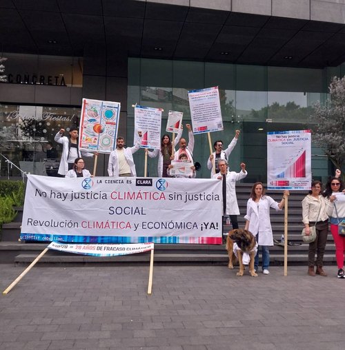 scientists stand together holding several signs and a banner that reads no hay justicia climatica sin justicia social