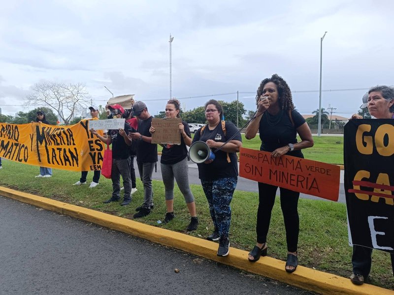 scientists and protestors hold signs on the side of a road
